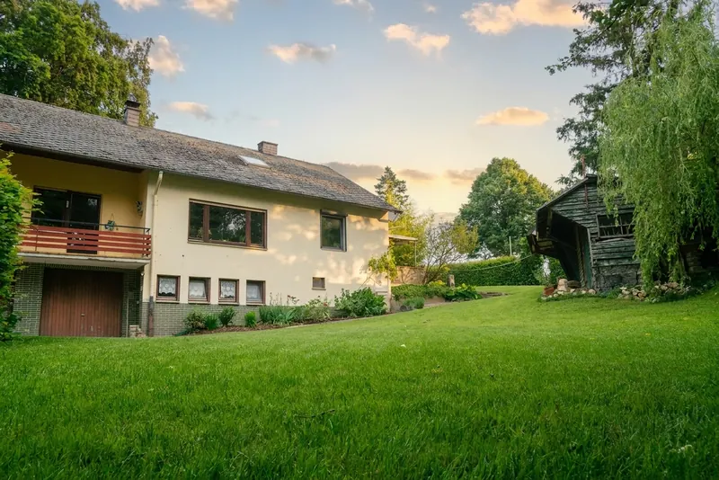Südseite des Haupthauses mit Garten und Holzschuppen im Abendlicht