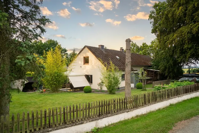 Das Haus mit Garten und Holzzaun im warmen Abendlicht