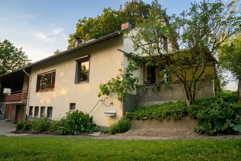 Blick vom überdachten Outdoor-Lounge-Bereich zum Haus