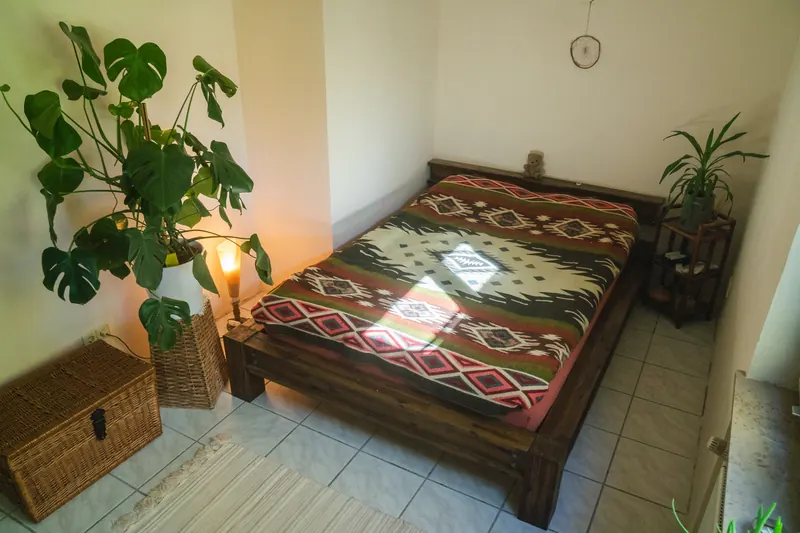 Schlafzimmer mit Holzbett und ethnisch gemustertem Plaid
