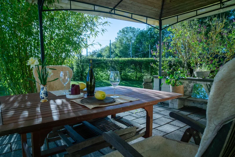 Überdachte Ostterrasse mit Esstisch und Gartenblick