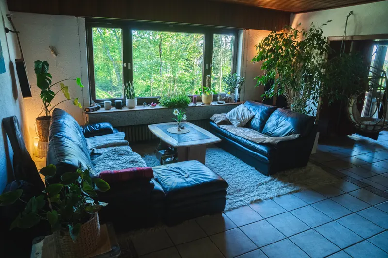 Wohnzimmer mit Couch-Ecke und großen Fenstern zum Garten